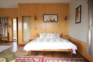 a bedroom with a large bed in a room with wooden walls at The Windbloom - Himalayan Farm Stay in Mukteshwar