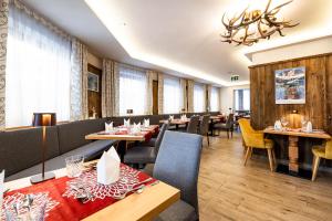 a restaurant with tables and chairs and a chandelier at Hotel Alpenrose in Zauchensee