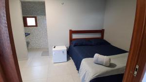 a small bedroom with two beds and a small refrigerator at Chalé Lá Aurora in Guaramiranga