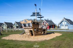 a wooden playground in a park with houses at Ferienhaus Nordseeresort 55 Meerglück Büsum in Büsum +29 photos