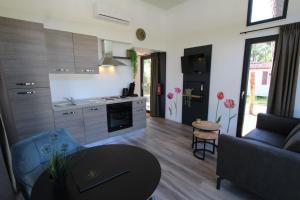 a kitchen and living room with a couch and a table at Knusse Tiny House in de natuur in Baarle-Nassau