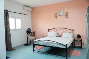 a bedroom with a bed and a pink wall at Gite de la savane in Sindia
