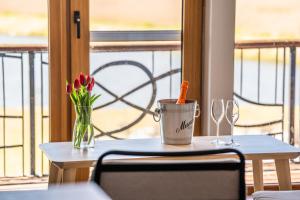 a table with a vase of flowers and glasses on a balcony at Svencelė Resort in Svencelė
