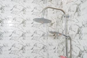 a shower with two shower heads on a white brick wall at Gite de la savane in Sindia
