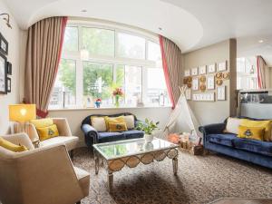 a living room with blue furniture and a large window at Mercure Doncaster Centre Danum Hotel in Doncaster