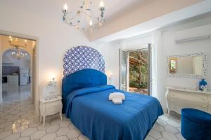 a bedroom with a blue bed and a bathroom at YourHome - Relais Casa degli Angeli in Positano