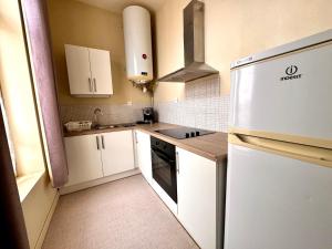 a small kitchen with white cabinets and a refrigerator at Le Repère de Rumaucourt in Rumaucourt