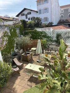a patio with tables and chairs and a umbrella at Mosaik hotel in Saint-Jean-de-Luz