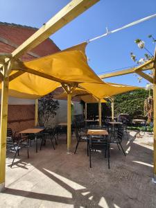 a group of tables and chairs under a yellow umbrella at Hotel Rural Papasol in Atapuerca