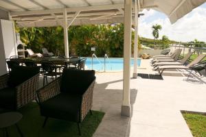 a patio with a table and chairs and a pool at Villa Diams Diamond in Le Diamant