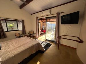 a bedroom with a bed and a tv on the wall at Chalé Mon Amour com sua piscina privativa in São Miguel do Gostoso