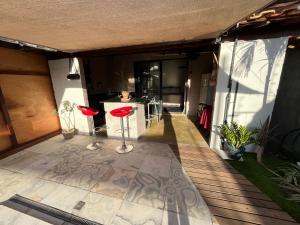 a patio with two red stools on a deck at Chalé Mon Amour com sua piscina privativa in São Miguel do Gostoso
