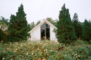 a small white house in a field of flowers at Veco Pine in Thạch Cầu