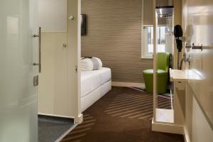 a bathroom with a bed and a green chair at hub London - Spitalfields in London