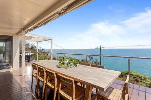 a dining table on a balcony with a view of the ocean at Clifftop Coastal Sanctuary Panoramic Views in Mount Martha