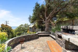 a backyard with a stone wall and a tree at Clifftop Coastal Sanctuary Panoramic Views in Mount Martha