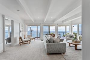 a living room with white furniture and a view of the ocean at Clifftop Coastal Sanctuary Panoramic Views in Mount Martha +22 photos