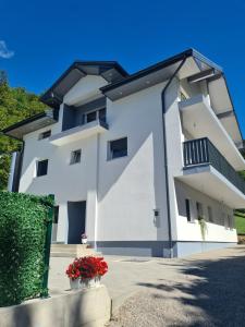 a white building with red flowers in front of it at Apartman Sunce in Jerkovići