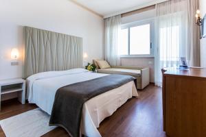 a hotel room with a large bed and a window at Hotel Benini in Milano Marittima