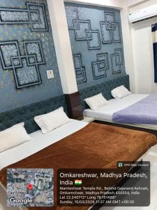 two beds in a room with a wall with pictures on it at Hotel Sadashiv in Godarpura