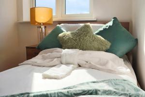 a bed with green pillows and a blanket at Luxury Heathrow Modern House with Parking & Fast WiFi in Northolt