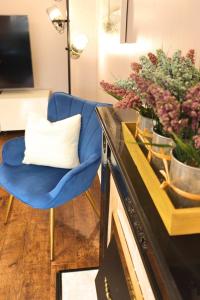 a living room with a blue chair and a vase of flowers at Luxury Heathrow Modern House with Parking & Fast WiFi in Northolt