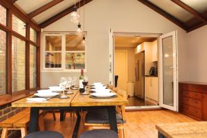 a dining room with a wooden table with wine glasses at Luxury Heathrow Modern House with Parking & Fast WiFi in Northolt