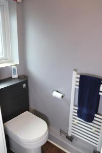 a bathroom with a toilet and a blue towel at Luxury Heathrow Modern House with Parking & Fast WiFi in Northolt +46 photos