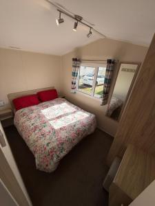 a small bedroom with a bed and a mirror at Seaside Caravan in a Leisure Park with WiFi & Parking - 3 bedrooms in Meliden