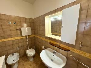 a bathroom with a sink and a toilet and a mirror at Condominio Piscina in Grado +7 photos
