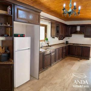 a kitchen with a white refrigerator and wooden cabinets at ANDA villa&Farm in Amman +27 photos
