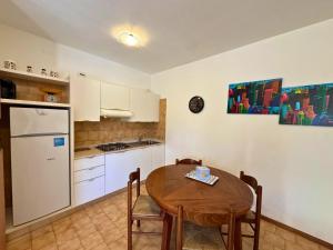 a kitchen with a table and a white refrigerator at Condominio Piscina in Grado