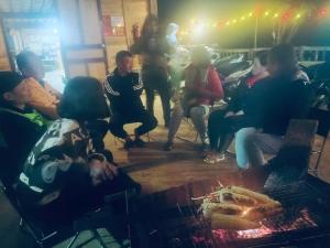a group of people sitting around a table with a grill at Sơn Tra Our House in Bản Bé