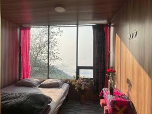 a bedroom with two beds and a large window at Sơn Tra Our House in Bản Bé