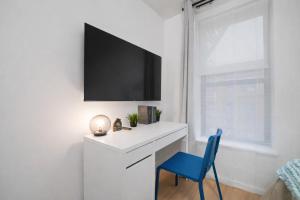 a white desk with a blue chair and a tv on a wall at Cozy 4BD Unit in Lower Manhattan in New York +7 photos