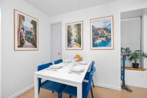 a white dining room with a white table and blue chairs at Cozy 4BD Unit in Lower Manhattan in New York