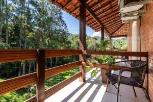 a balcony with chairs and a view of the woods at Recanto de Moriá in Penedo