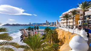 a view of a beach with palm trees and buildings at Villa Horizonte in Finestrat