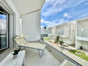 a balcony with a chair and a large window at Villa 124 Residence in Lignano Sabbiadoro