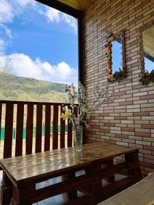 a wooden table with a vase of flowers on a balcony at racha cozy cottage in Ambrolauri