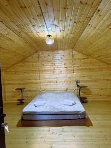 a room with a bed in a wooden room at racha cozy cottage in Ambrolauri