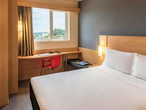 a hotel room with a bed and a desk and a window at ibis Chapeco in Chapecó +53 photos