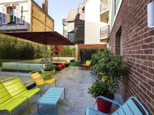 a patio with chairs and tables and an umbrella at ibis Styles Deauville Centre in Deauville