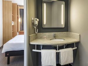 a bathroom with a sink and a mirror and a bed at ibis Santos Valongo in Santos +57 photos