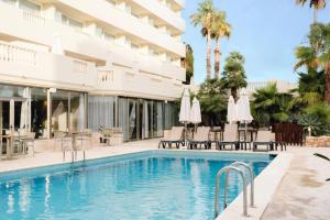 a swimming pool with chairs and umbrellas next to a hotel at BLUESEA Paraiso Beach - Adults Only in Es Cana