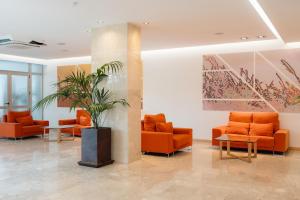 a lobby with orange chairs and a potted plant at BLUESEA Salina Ex MD Atlantic in Es Cana