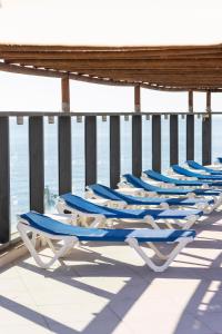 a row of blue and white lounge chairs on a balcony at BLUESEA Calabahía in Cala del Moral