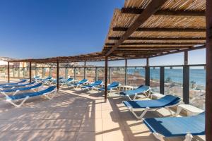a row of lounge chairs and the ocean at BLUESEA Calabahía in Cala del Moral