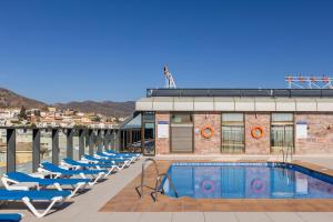 a row of lounge chairs next to a swimming pool at BLUESEA Calabahía in Cala del Moral