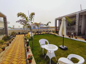 a patio with white chairs and a table and umbrella at White Coastal Beach Resort in Mandarmoni